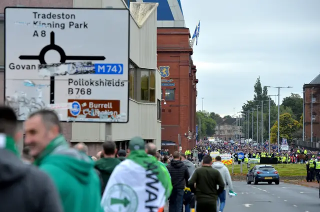 Celtic supporters arriving at Ibrox, with Rangers fans in the distance also making their way to the stadium