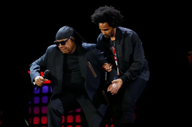 Stevie Wonder takes a knee with the help of his son Kwame Wonder