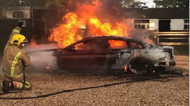 Burning car being put out by a firefighter