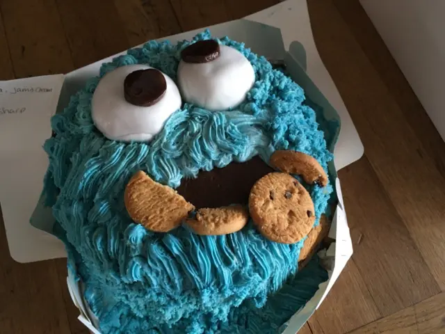 A cake with blue icing in the shape of a monster's face