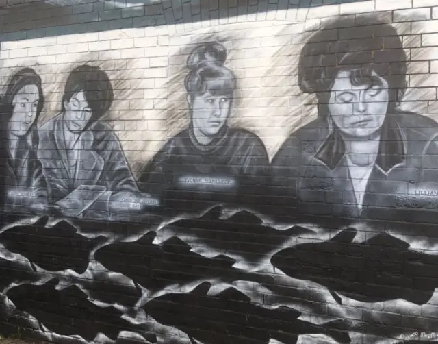 Mural on wall showing 4 women with fish swimming below them.