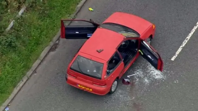 Aerial shot of red car showing bullet holes