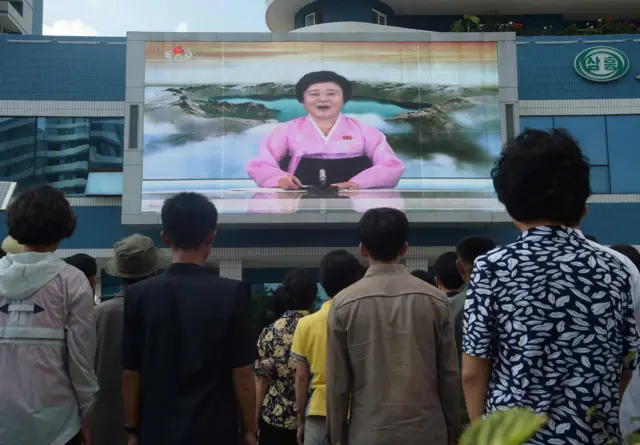 People watching a large public TV screen