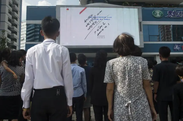 People watching a giant public TV screen