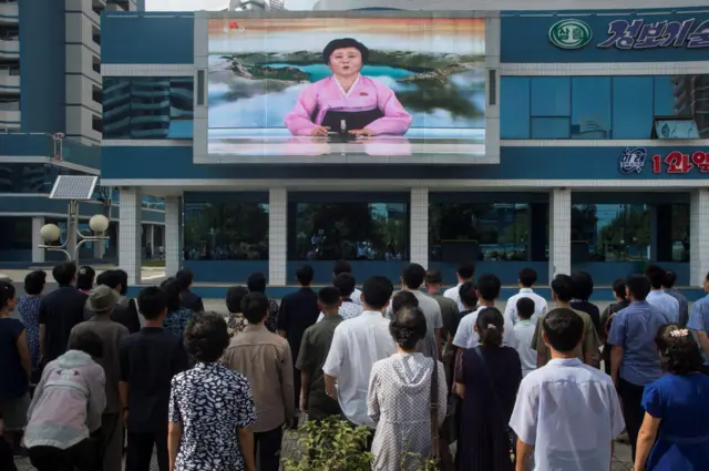 People watching a giant public TV screen