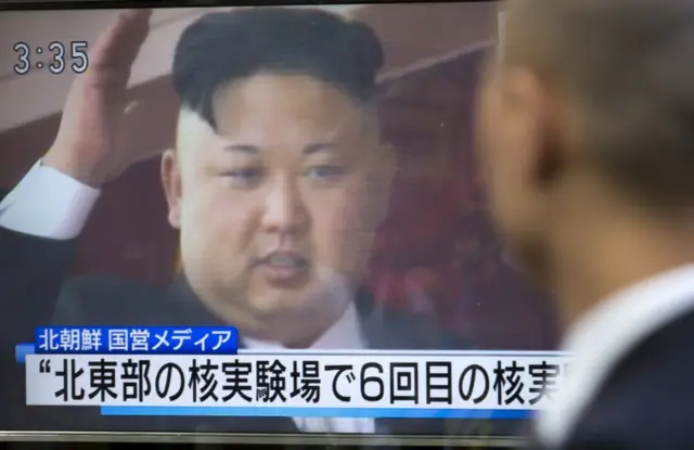 :A pedestrian in Tokyo watches a monitor showing an image of North Korean leader Kim Jong-Un