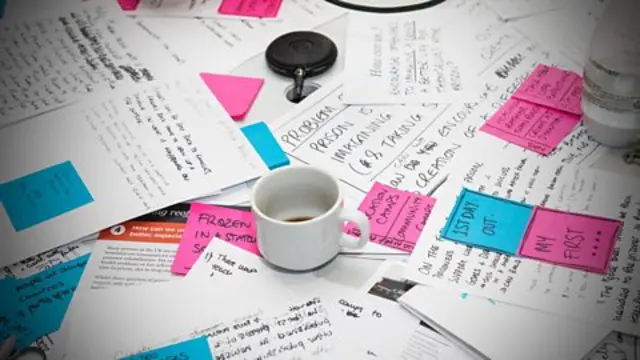 Written papers and a coffee cup messily strewn on a table.