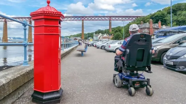 Chap in wheelchair by postbox next to Forth Bridge