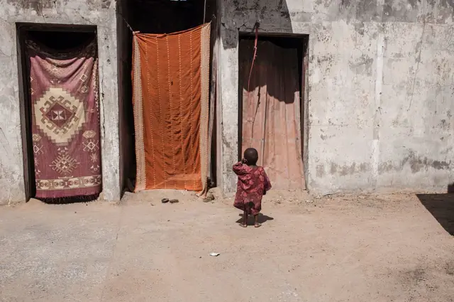 A young child stands by a doorway in an IDP camp in Nigeria