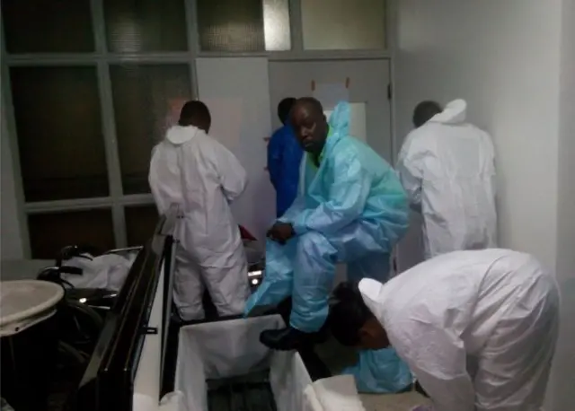 Dr Madiebo, pictured next to the coffin, and a team of morticians worked together to remove the body of Patrick Sawyer