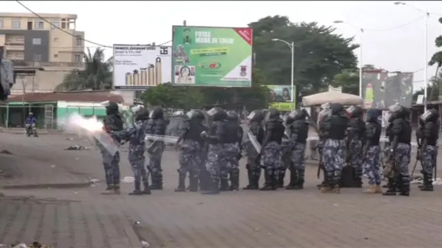 An officer is seen firing tear gas at protesters