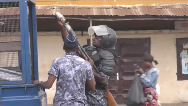 An officer is seen loading what appears to be a canister of tear gas