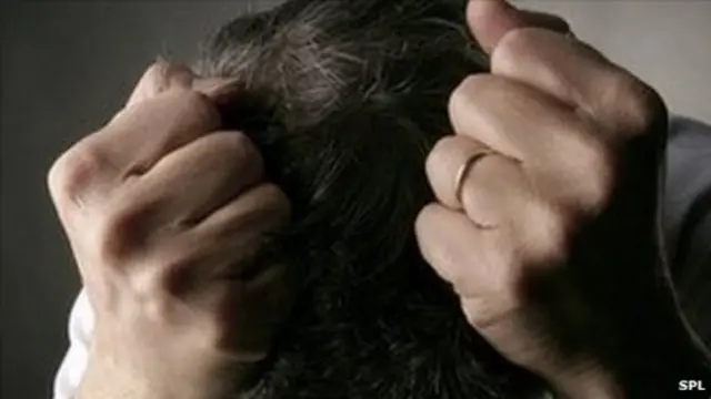 A man clutching his head.