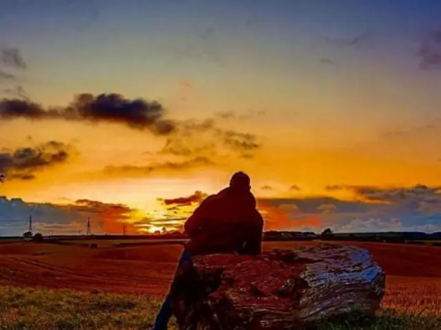 The silhouette of a man against the sunrise.