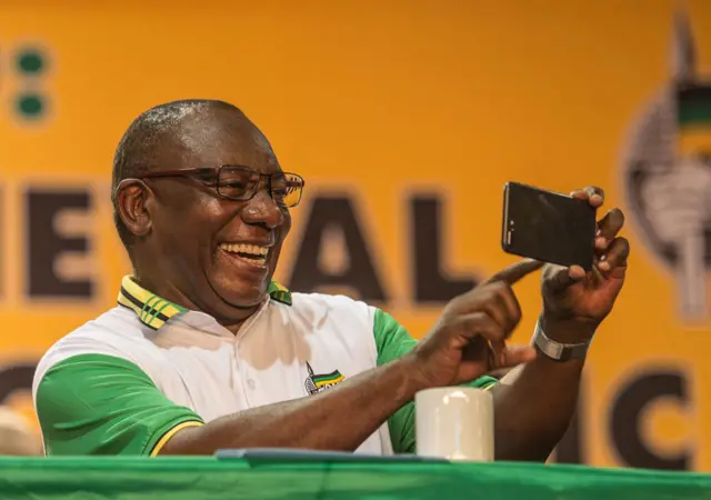 Newly elected African National Congress (ANC) President and current South African deputy President Cyril Ramaphosa takes images of unseen media representatives with his cellular telephone at the 54th ANC conference in Johannesburg on December 18. 2017