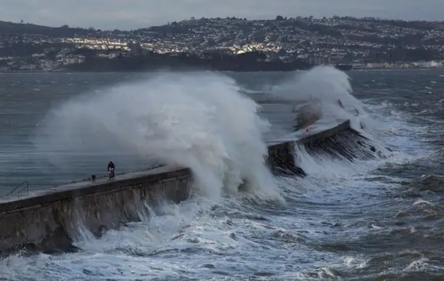 Man and dog beneath wave in Brixham