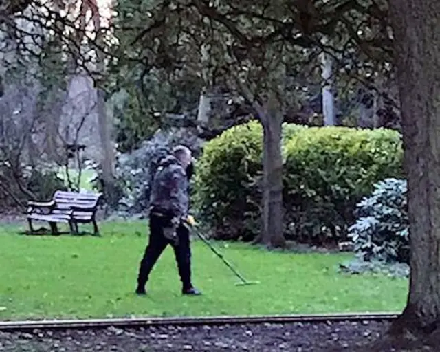 Man using a metal detector in Hotham Park, Bognor