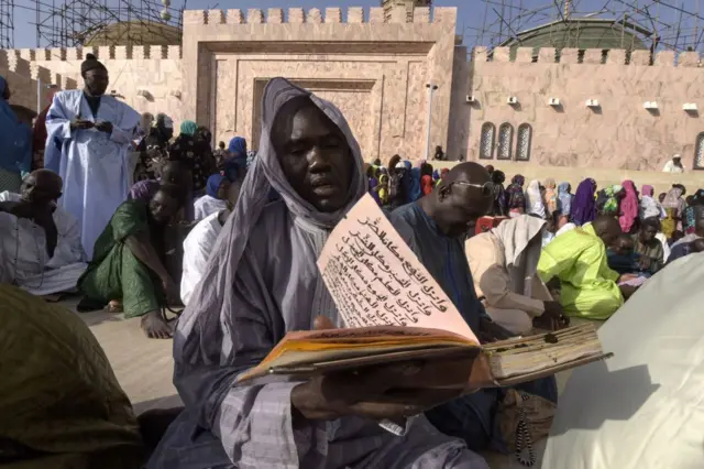 A member of the Mouride Brotherhood, a large Sufi order largely present in Senegal, reads a religious book outside the Great Mosque in Touba on November 19, 2016 during the religious festival of the Magal and the 122nd edition of celebrations of the return from exile of its founder, the great marabout Sheikh Amadou Baba.