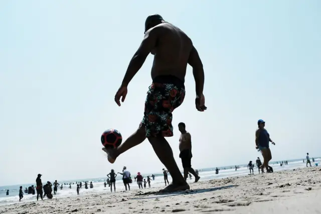 A man on the beach plays football