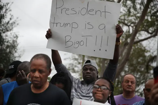 Jorel Francois holds a sign that reads, 'President trump is a Bigot!!!'