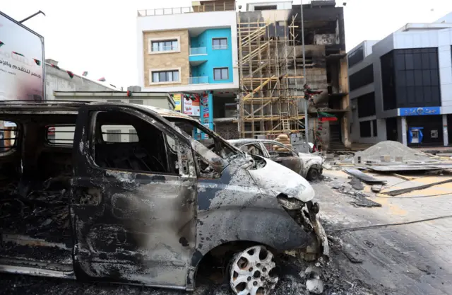 Charred vehicles are pictured outside the quarters of the Libyan Al-Nabaa TV channel in the capital Tripoli, following exchanges of rocket and artillery fire between unity government forces and a militia loyal to a former prime minister on March 15, 2017