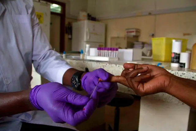 A lab technician draws blood from a patient