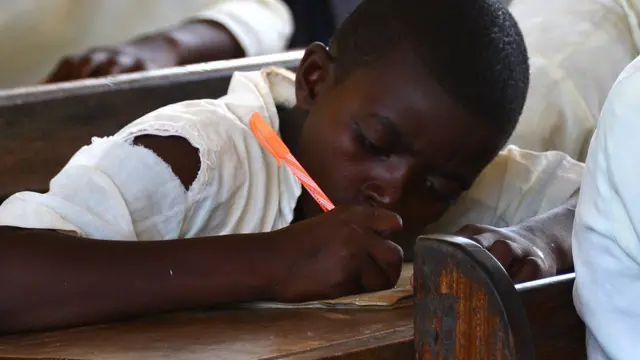 A school pupil sitting a desk concentrates on his work