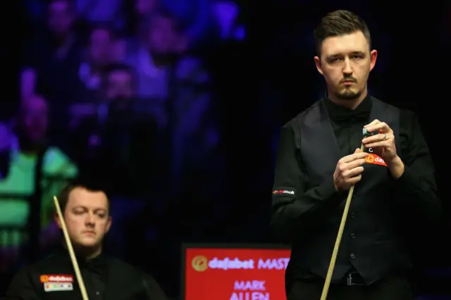 Kyren Wilson chalks his que as Mark Allen watches on