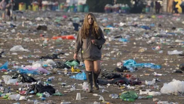 Reveller wades through Glastonbury wasteland