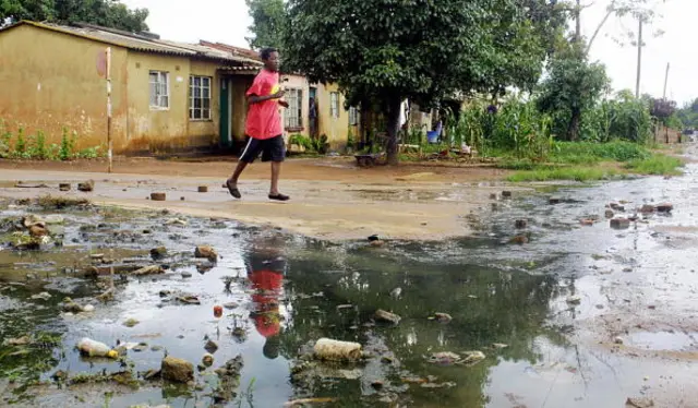 A man crosses a street flooded by sewage in the township of Dzivaresekwa in Harare, 01 March 2006.