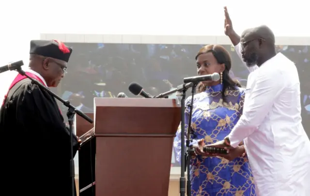 iberia"s new President George Weah raises his hand during the swearing-in ceremony at the Samuel Kanyon Doe Sports Complex in Monrovia, Liberia, January 22, 2018.