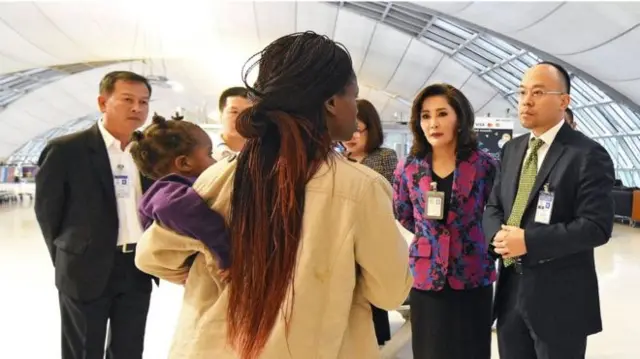 Zimbabwean mother with her infant daughter surrounded by Thai officials inside the airport