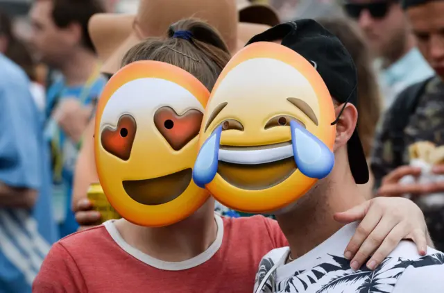 People wear emoji masks in the crowd in front of the Pyramid stage at Glastonbury