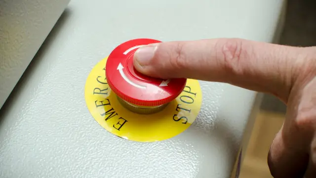 A finger on an emergency stop button