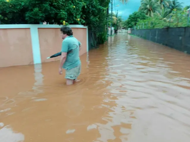 A man stands with his umbrella in a flooded street