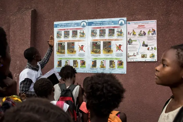 People inspect a cholera poster in Kinshasa in January 2018