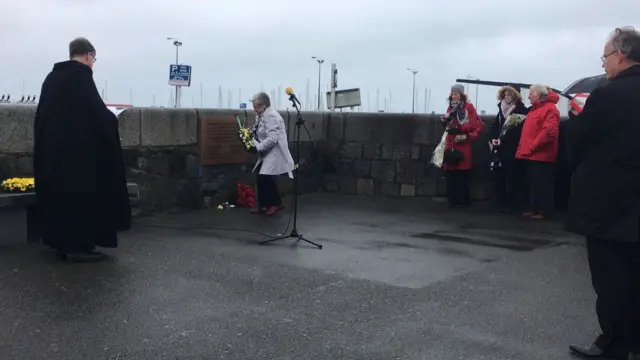 Jean Harris lays flowers at a plaque to remember her father, Joseph Gillingham, and seven other Guernsey resisters who died in Nazi prisons and concentration camps.