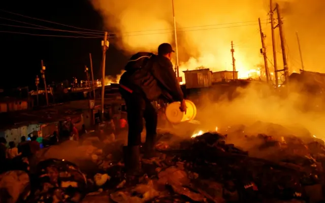 A resident attempts to extinguish a fire that broke out at the Kijiji slums in the Southlands estate of Nairobi, Kenya, January 28, 2018.