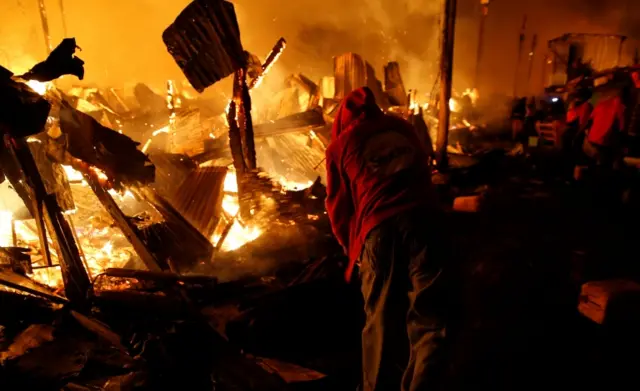 A resident attempts to extinguish a fire that broke out at the Kijiji slums in Southlands estate of Nairobi, Kenya January 28, 2018.