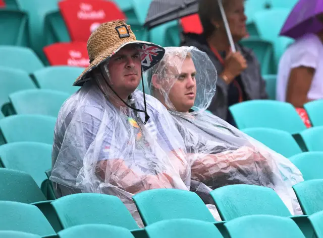 Fans shelter from the rain