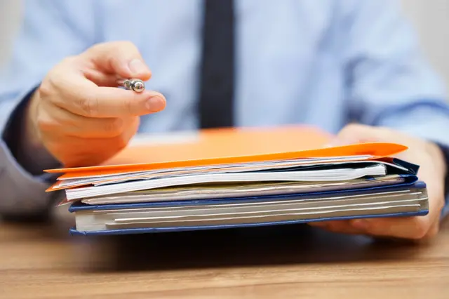 A person handing over folders