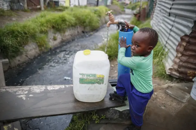 A child in Masiphumelele informal settlement collects drinking water from a communal municipal tap in Cape Town, South Africa, 30 January 2018