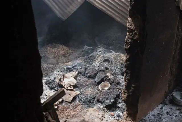 A picture taken on February 24, 2017 shows a crop of beans lost as fire smoulders inside a damaged house in the village of Bakin Kogi, in Kaduna state, northwest Nigeria