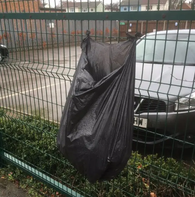 Black bin liner tied to a fence