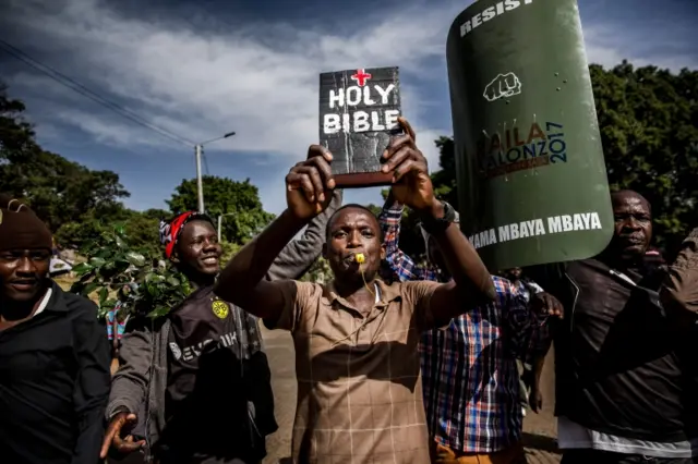 A man holds up a bible as supporters of the Kenyan opposition National Super Alliance (NASA) coalition leader react before he has himself sworn in as the "people"s president" on January 30, 2018 in Nairobi