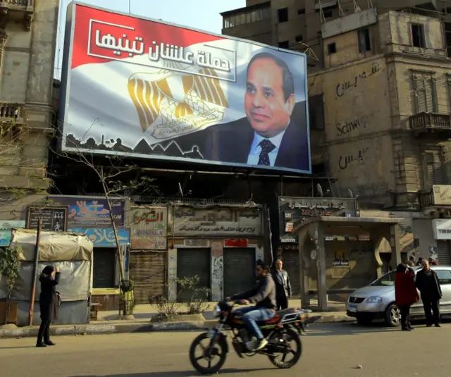 Egyptians walk underneath an election campaign poster erected by supporters of Egyptian President Abdel Fattah al-Sisi, in Cairo, Egypt, 28 January 2018.