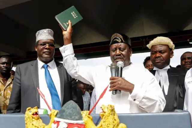 The leader of the Kenyan opposition National Super Alliance (NASA) Raila Odinga (C) raises a bible as he "takes an oath" during the "swearing-in" ceremony in Nairobi, Kenya, 30 January 2018