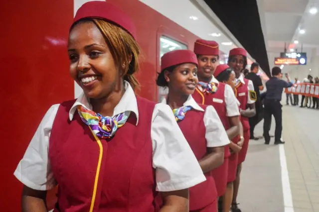 A line of stewardesses next to the  new train