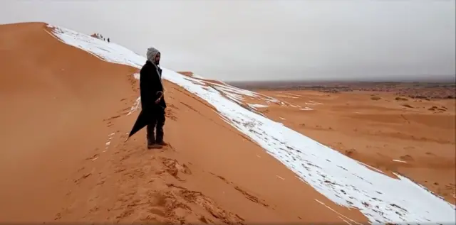 man looks at at a snow-covered slope in the Sahara, Ain Sefra, Algeria, January 7, 2018 in this picture obtained from social media.