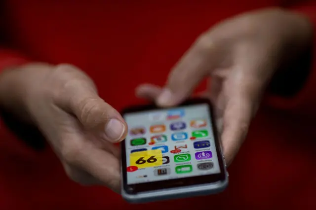 A woman holds a smartphone showing the Brazilian App for ridesharing 99 Taxi in Rio de Janeiro, Brazil, on January 4, 2018